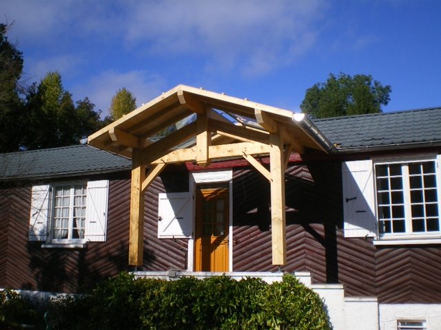 Auvent en bois à deux pans devant l'entrée d'une maison