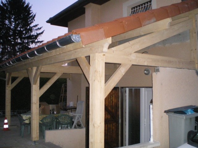 Auvent en bois adossé à une maison, au-dessus d'une terrasse
