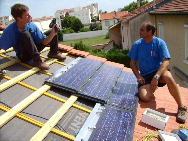Deux artisans posent des panneaux solaires sur un toit
