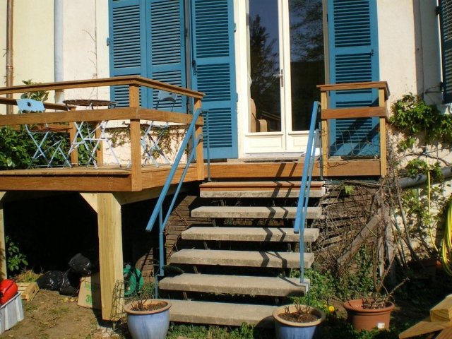 Terrasse en bois avec escalier devant des volets bleus