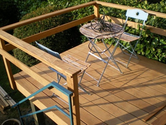Terrasse en bois avec une table et des chaises, entourée d'une rambarde